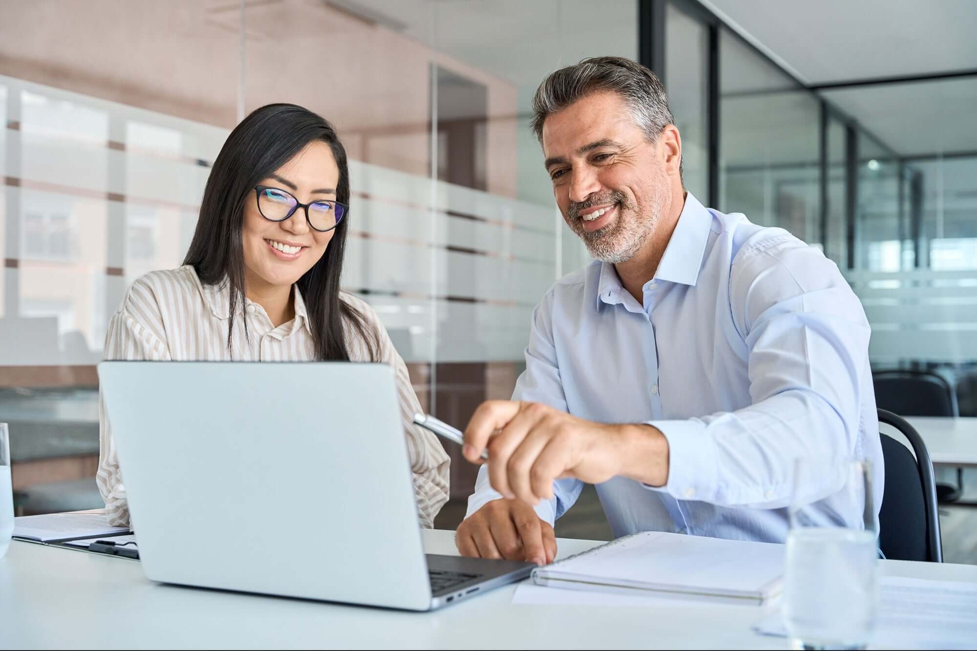 Colleagues smiling while reviewing laptop together